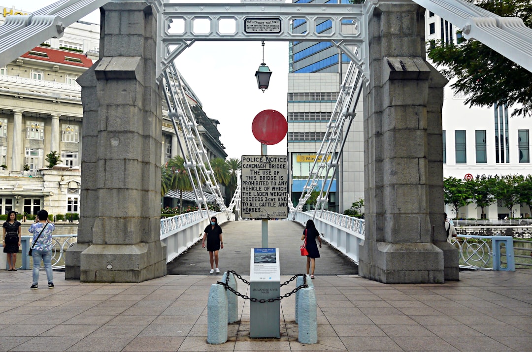 woman in white shirt and blue denim jeans standing on gray concrete bridge during daytime