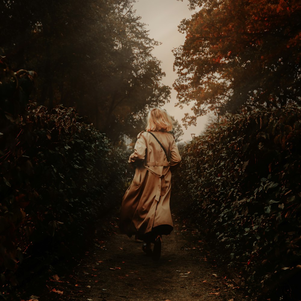 woman in white coat walking on forest during daytime