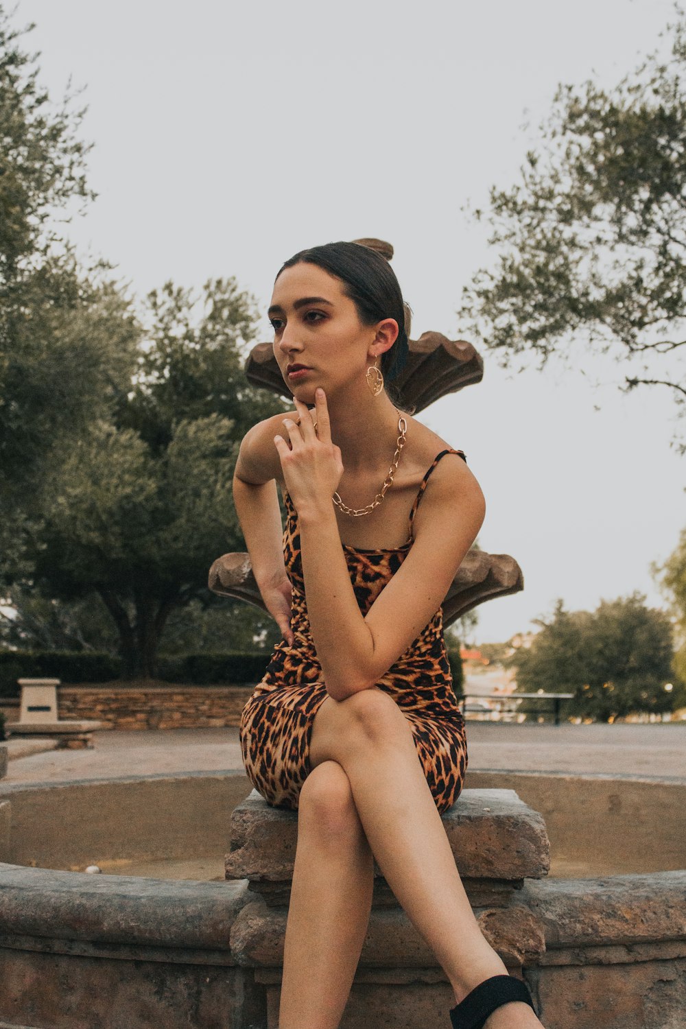 woman in leopard print dress sitting on concrete bench during daytime