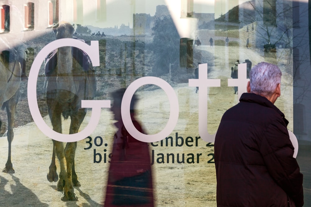 man in black hoodie standing near glass window