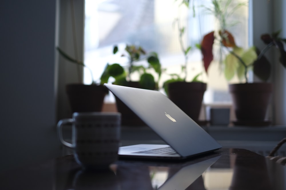 MacBook argenté sur table en bois marron