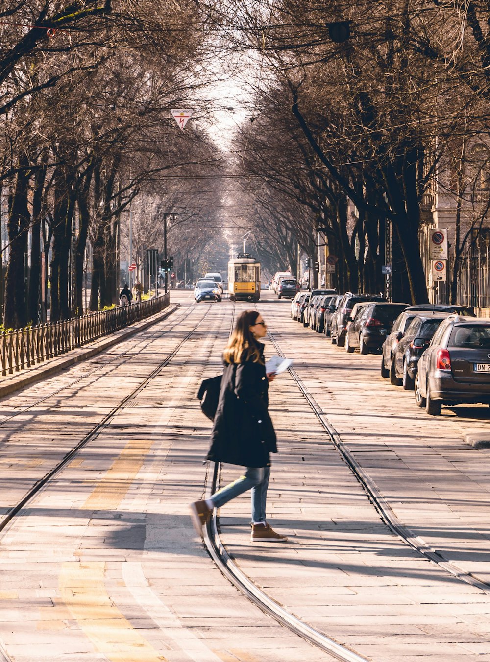 woman in black coat walking on sidewalk during daytime