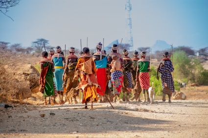 people in orange and yellow traditional dress walking on brown sand during daytime