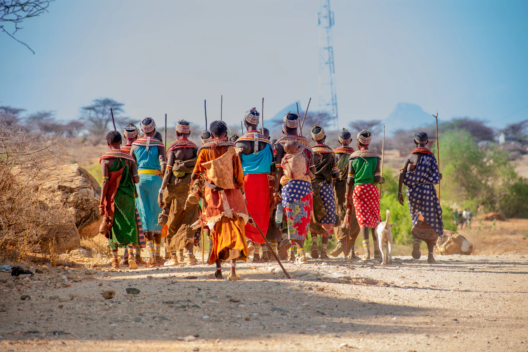 People in traditional dress walking across dry open ground in northern Kenya
