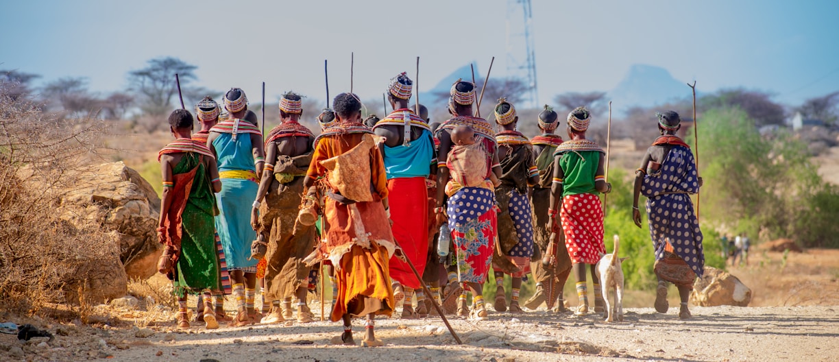 people in orange and yellow traditional dress walking on brown sand during daytime