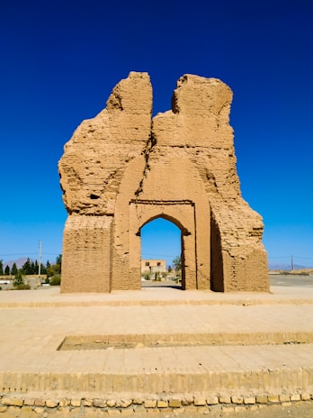 An ancient, rune-covered stone archway standing alone in a windswept desert.