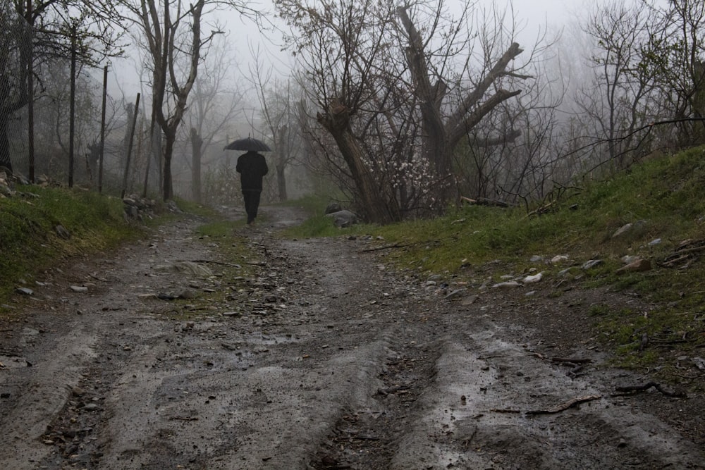 person in black jacket walking on dirt road