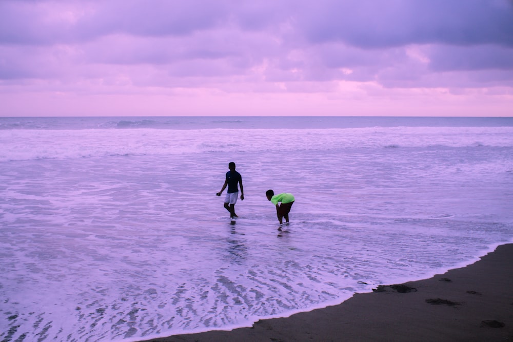 homme et femme se tenant la main tout en marchant sur la plage pendant la journée