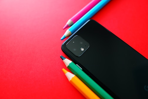 black phone beside green and white pen