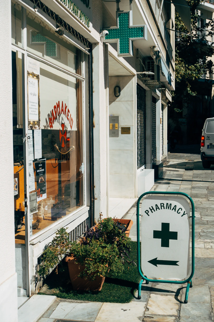 Fachada de farmacia con el aviso y la cruz verde en la acera