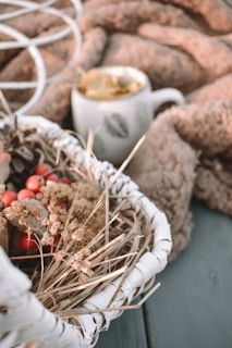Close-up of a luxurious coffee basket adorned with soft pink flowers and green leaves, set against a warm autumn background.