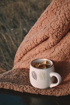 A cozy autumn kitchen with a steaming mug on a wooden table surrounded by colorful leaves.