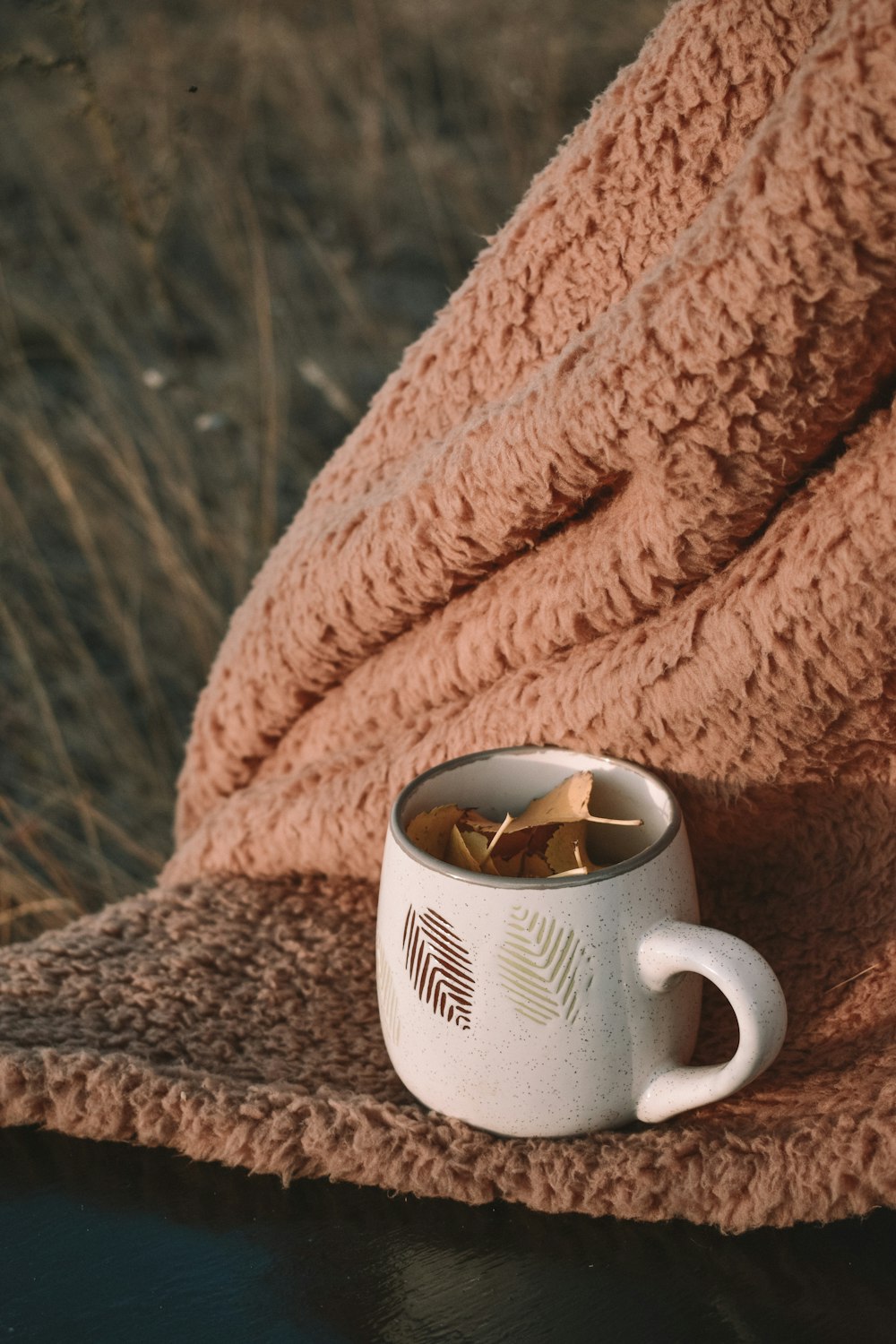 white and black ceramic mug on brown textile