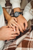 A close-up of intertwined hands resting on a picnic blanket with scattered comic books nearby.
