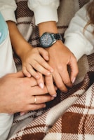 Close-up of intertwined hands resting gently on a cozy blanket, symbolizing connection.