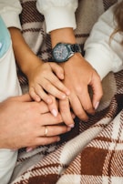 A close-up of hands intertwined, resting on a picnic blanket with soft sunlight.