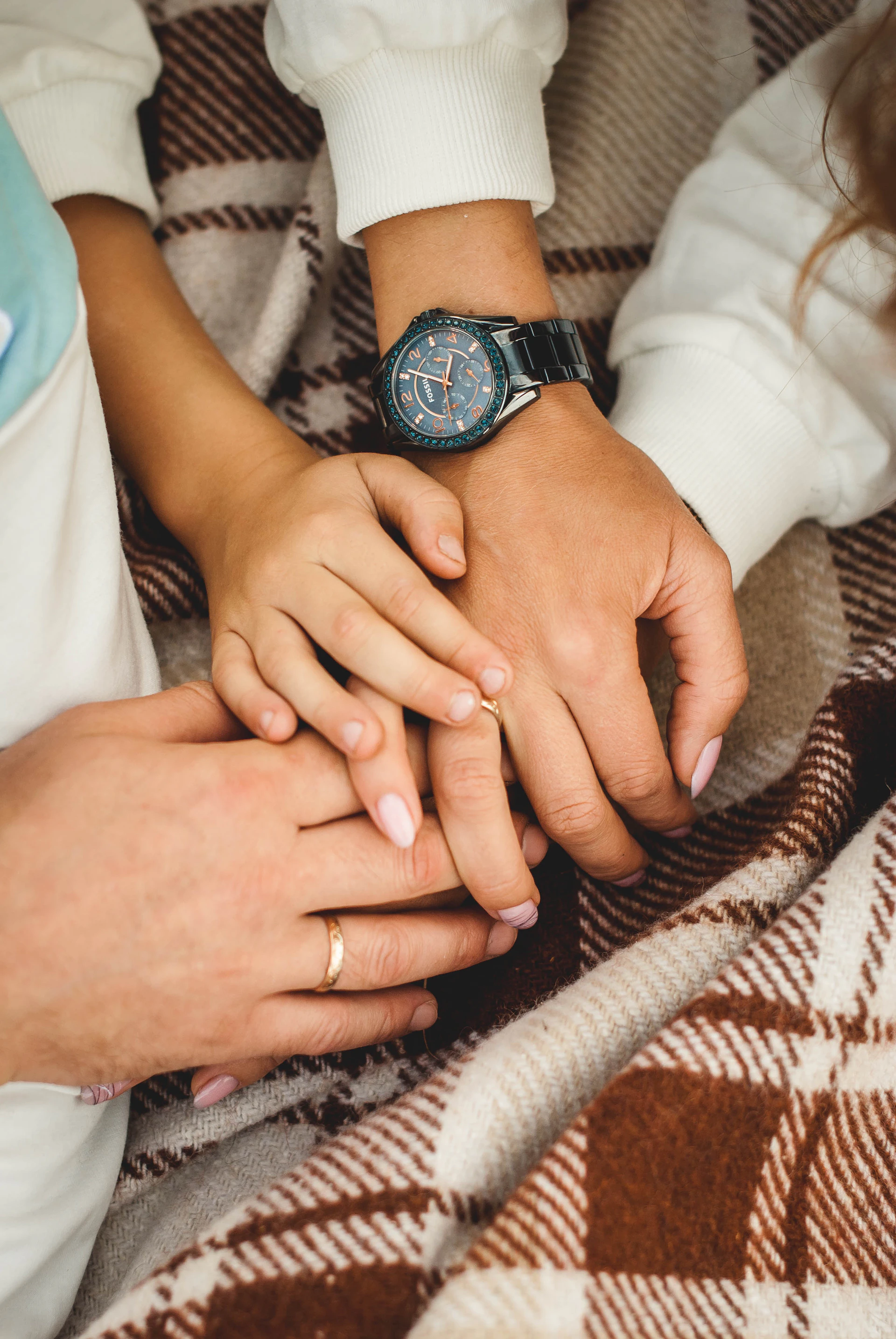 A close-up of intertwined hands resting on a cozy blanket, symbolizing trust and togetherness.