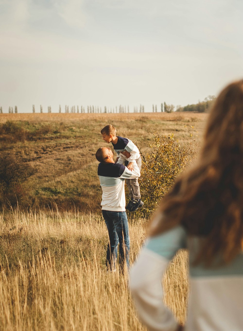 man and woman kissing on brown grass field during daytime