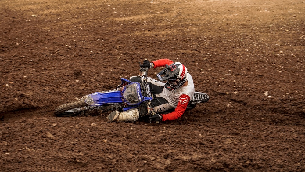 man in red and black jacket riding blue and white motocross dirt bike