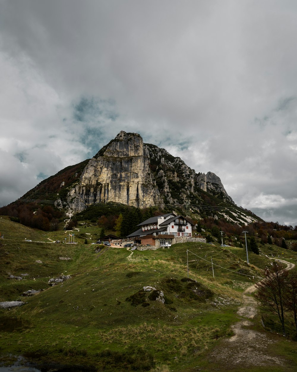 white and brown house near rocky mountain under cloudy sky during daytime