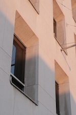 Exterior building facade being enhanced with decorative resin finishes under natural sunlight.