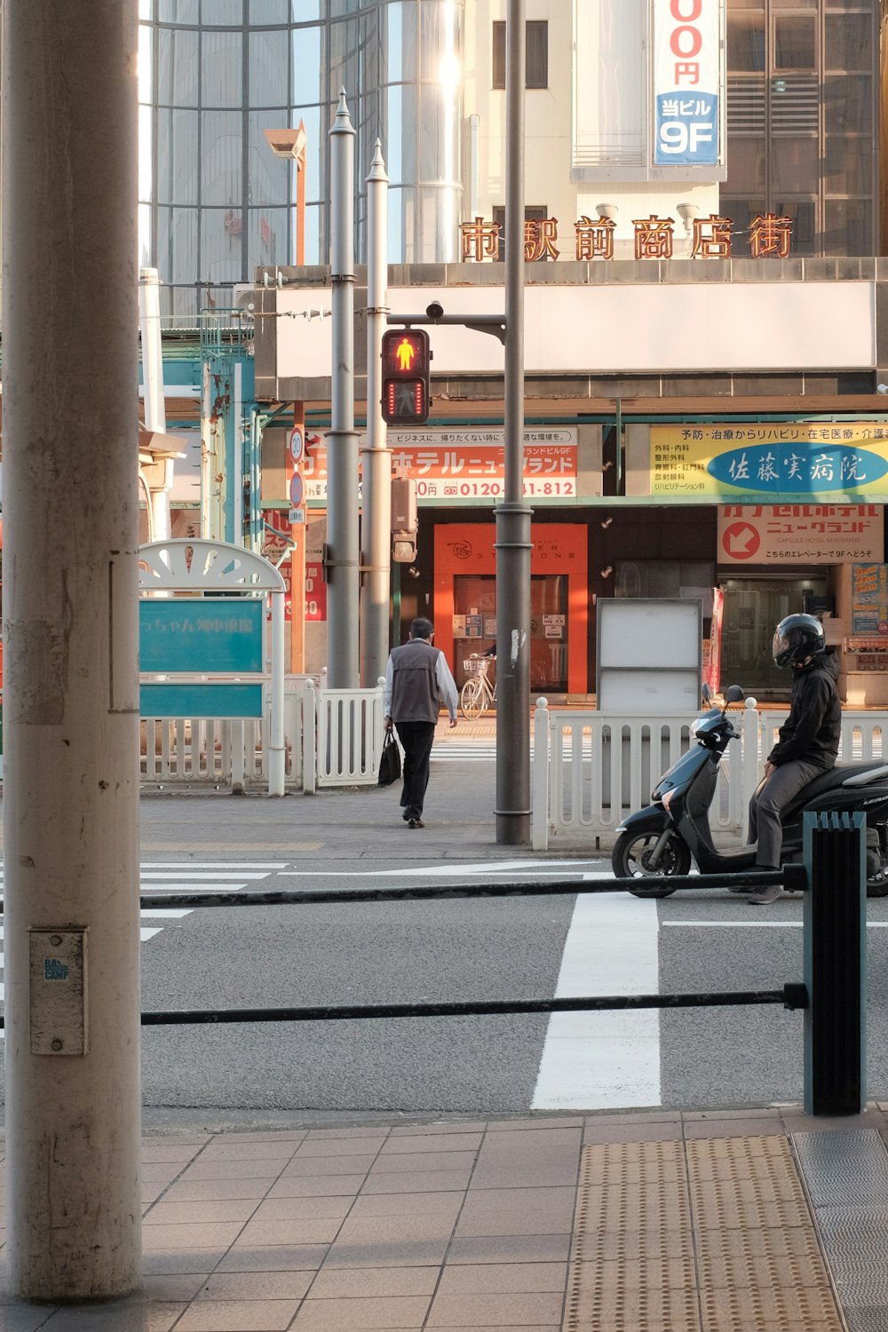 黒いジャケットと黒いズボンを着た男が、昼間の道路で黒いバイクに乗っている