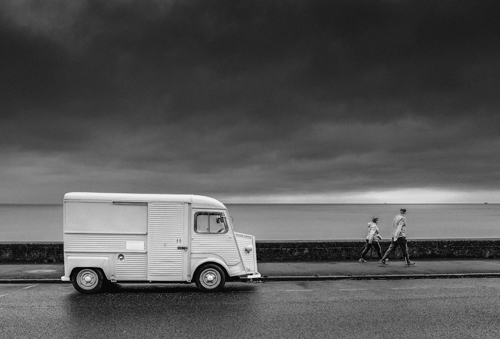 grayscale photo of man and woman walking on beach