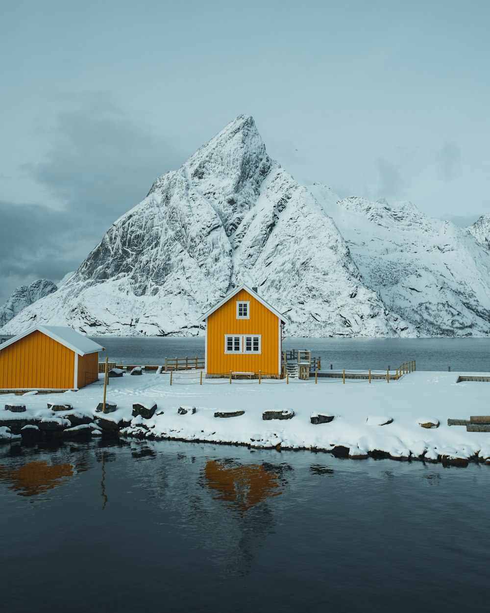 brown wooden house near snow covered mountain during daytime