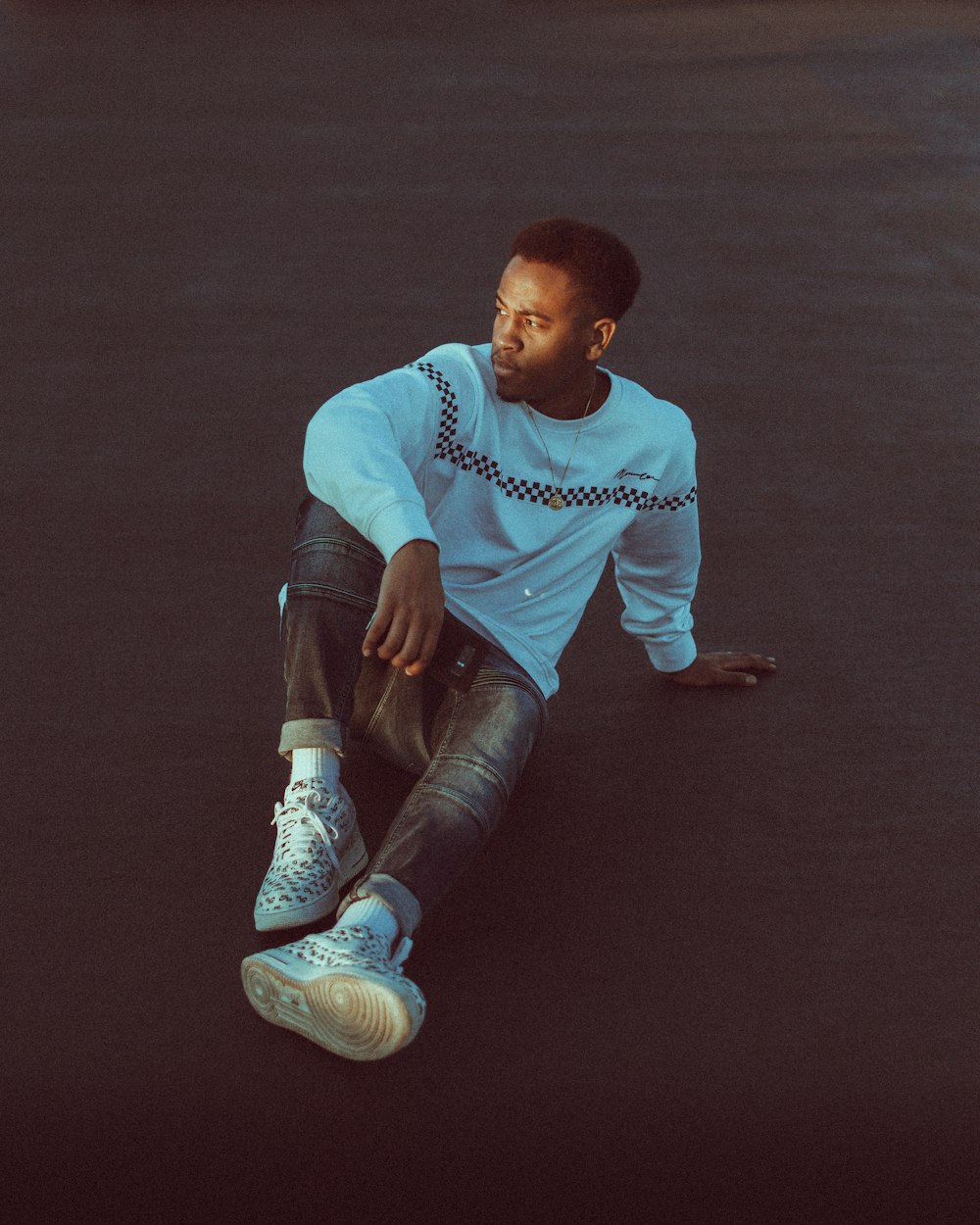 man in blue crew neck t-shirt and blue denim jeans sitting on floor