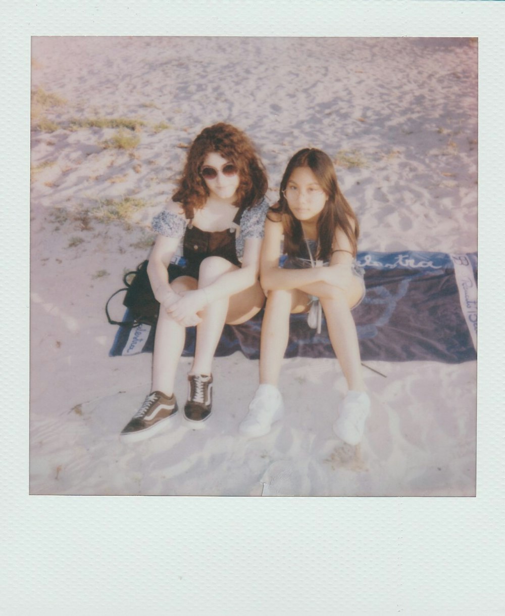 2 women sitting on blue textile