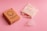 A cardboard box labeled 'OrganiCup' with green lettering lies on a pink surface next to a drawstring cloth bag and a translucent menstrual cup. The box has additional small icons and text, indicating product details.