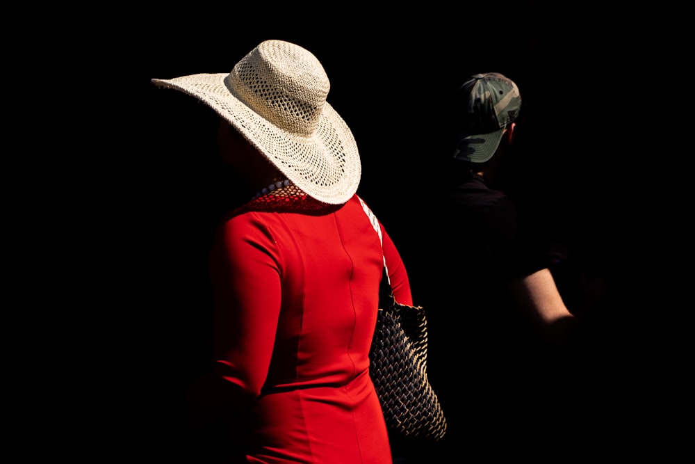 Mujer con vestido rojo de manga larga con sombrero blanco y negro