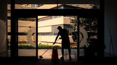 silhouette of man standing near glass window during daytime