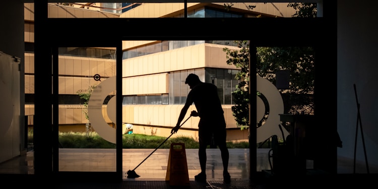 Man cleans floor at an entrance door.