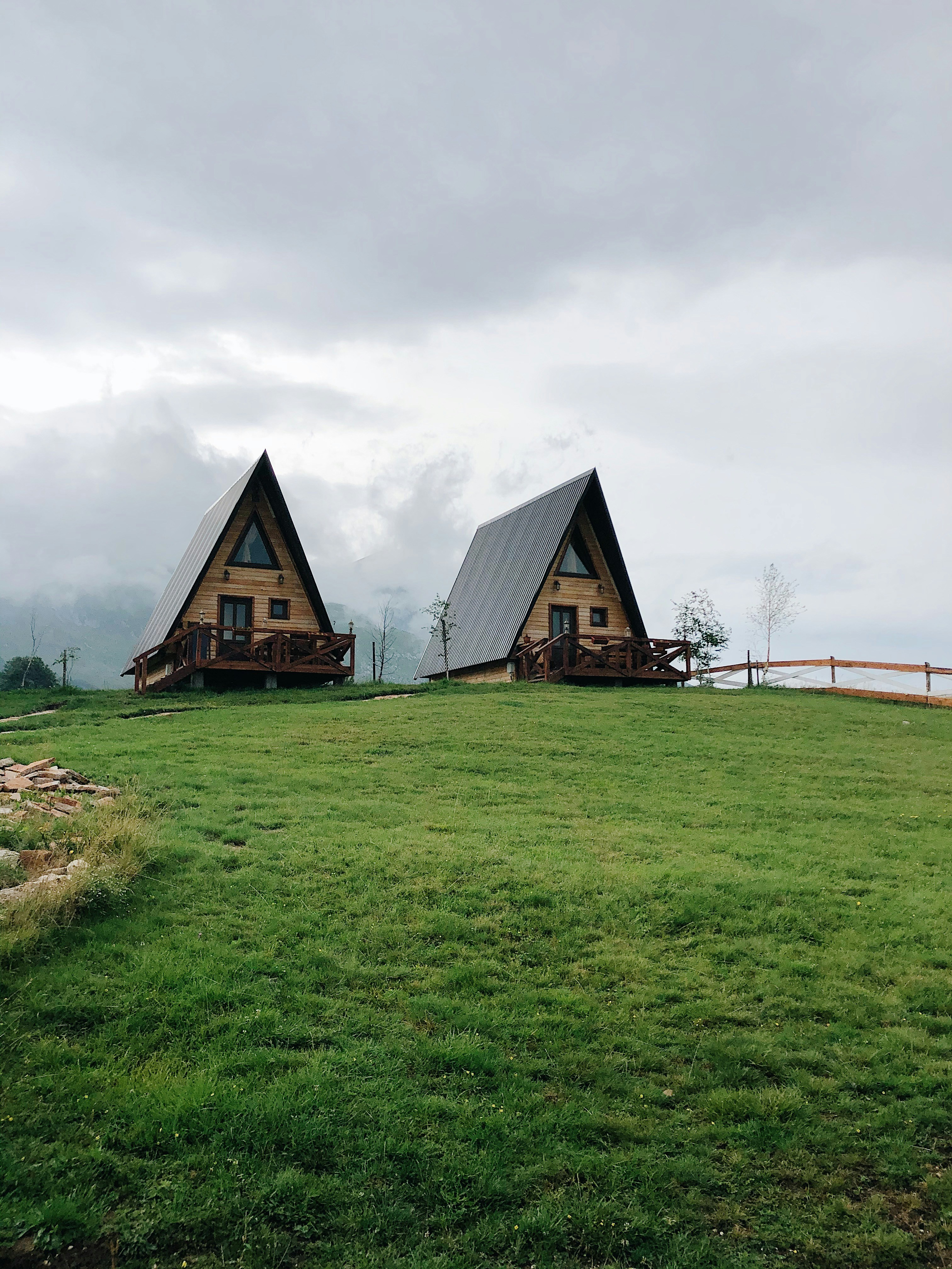 brown wooden house on green grass field under white cloudy sky during daytime