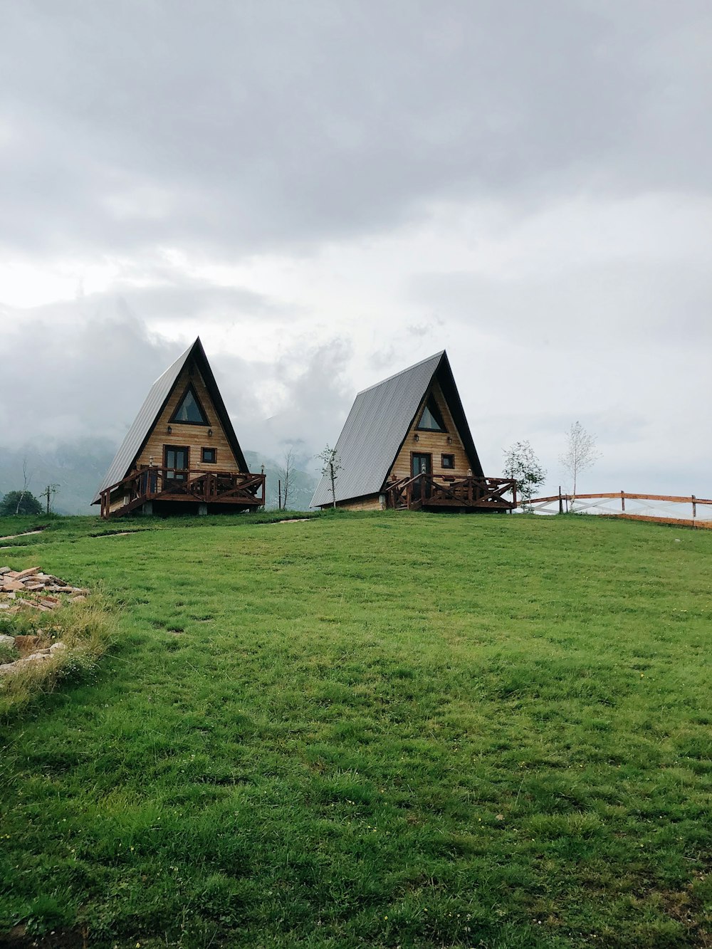 brown wooden house on green grass field under white cloudy sky during daytime