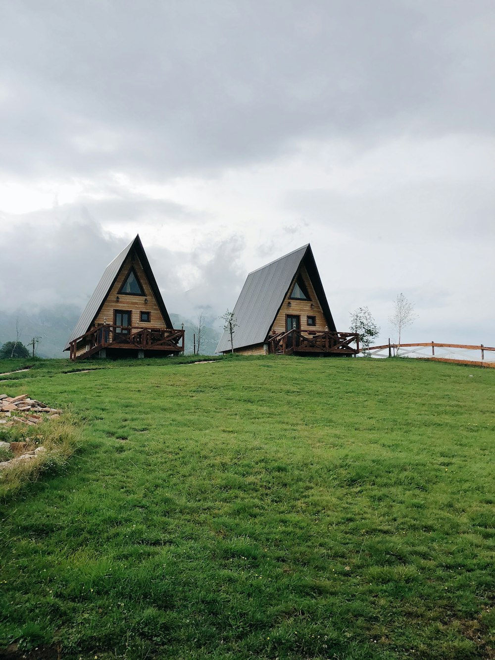 maison en bois marron sur un champ d’herbe verte sous un ciel nuageux blanc pendant la journée