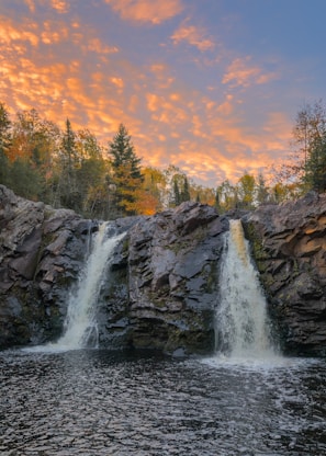 waterfalls on rocky mountain during sunset