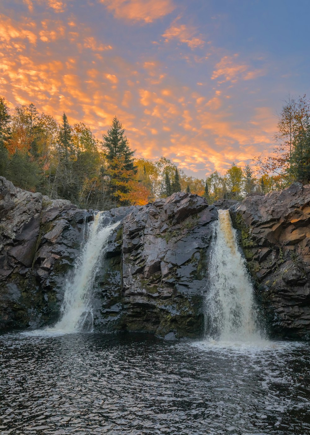 Cascate sulla montagna rocciosa durante il tramonto