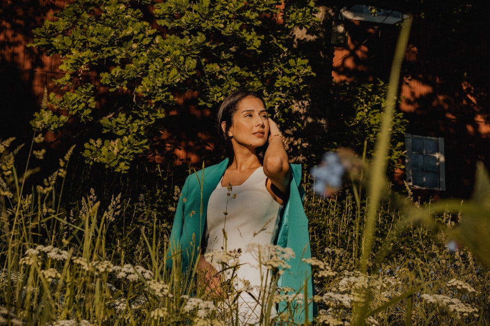 woman in white tank top and green blazer standing near green plants during daytime