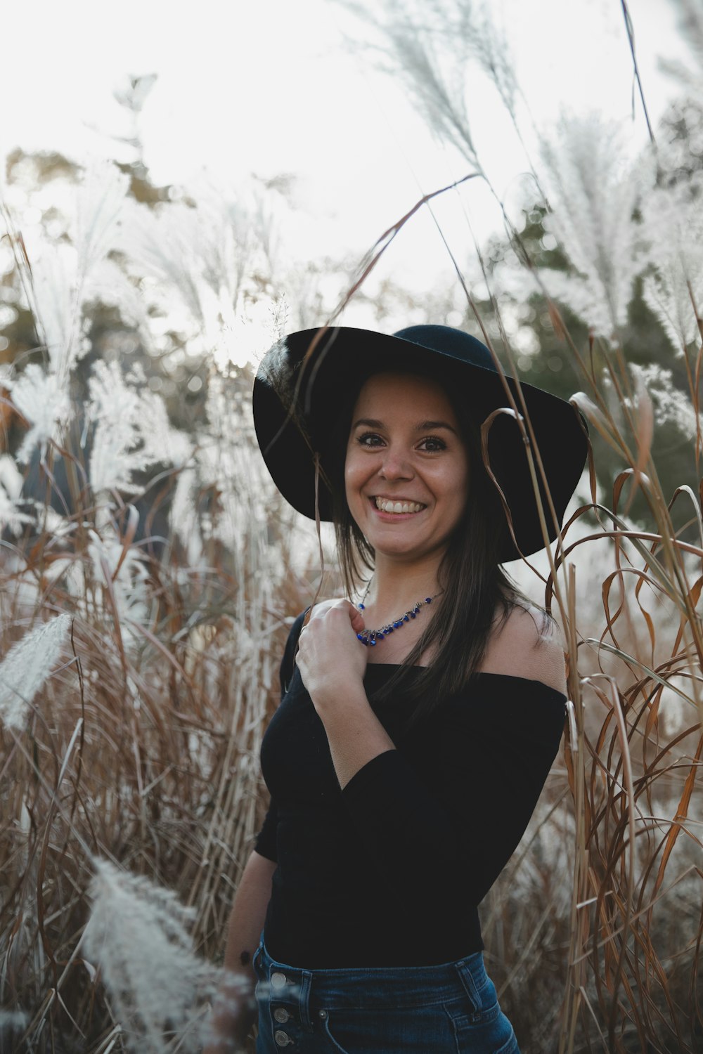 woman in black shirt wearing black hat standing on brown grass field during daytime