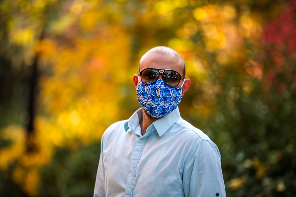 Uomo in camicia grigia abbottonata che indossa occhiali da sole blu