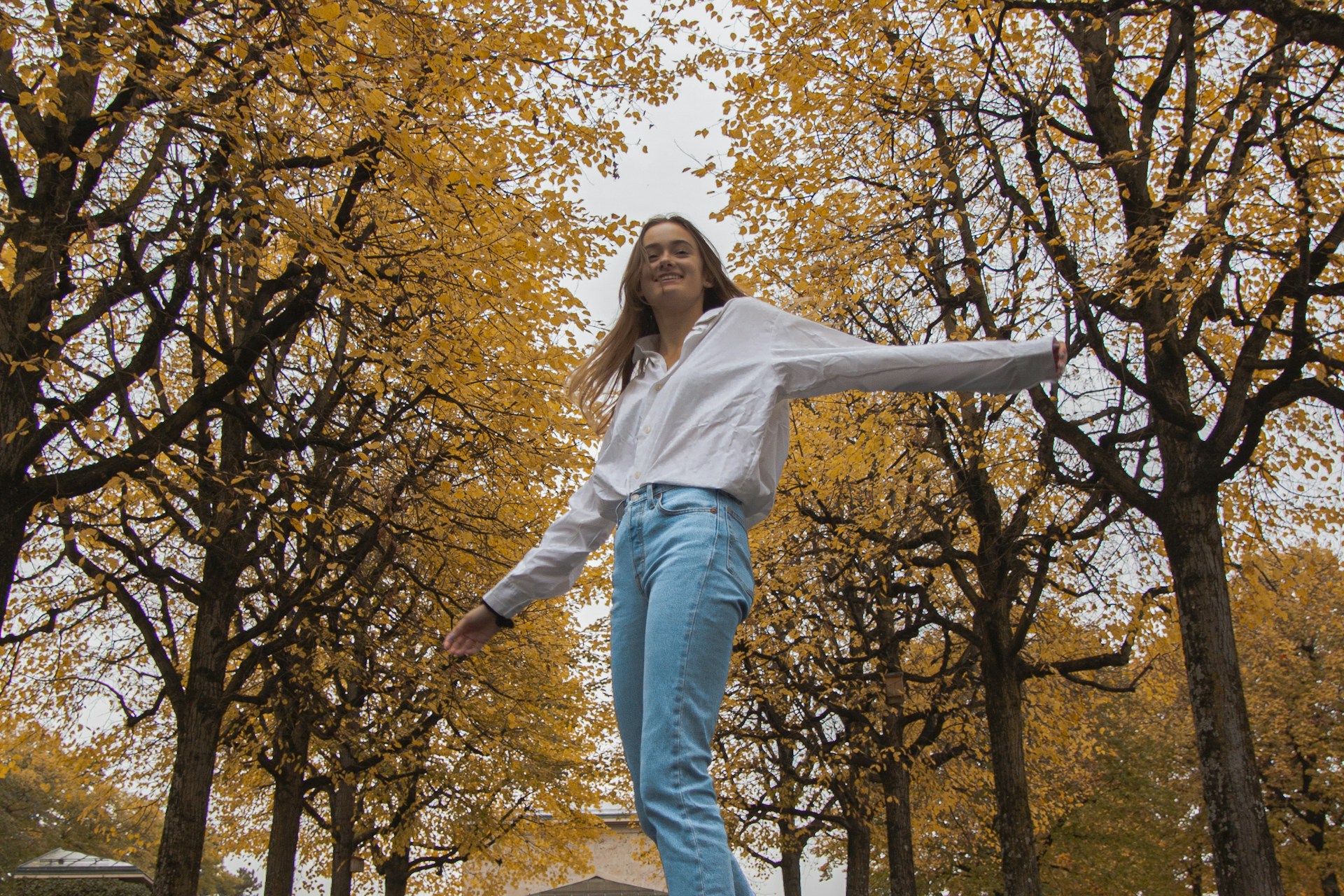 woman in white long sleeve shirt and blue denim jeans standing on white concrete bench during