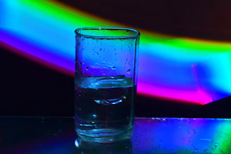 A refreshing bottle of crystal-clear water with droplets on the surface, set against a bright, natural background.