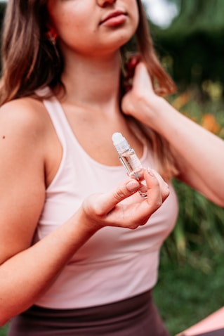 woman in white tank top holding white plastic bottle