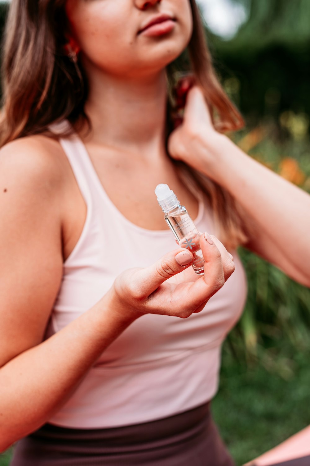 woman in white tank top holding white plastic bottle