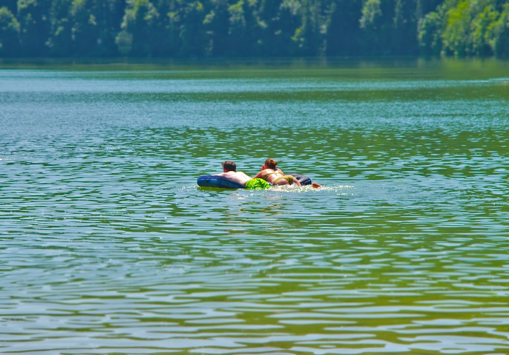 2 people swimming on green water during daytime