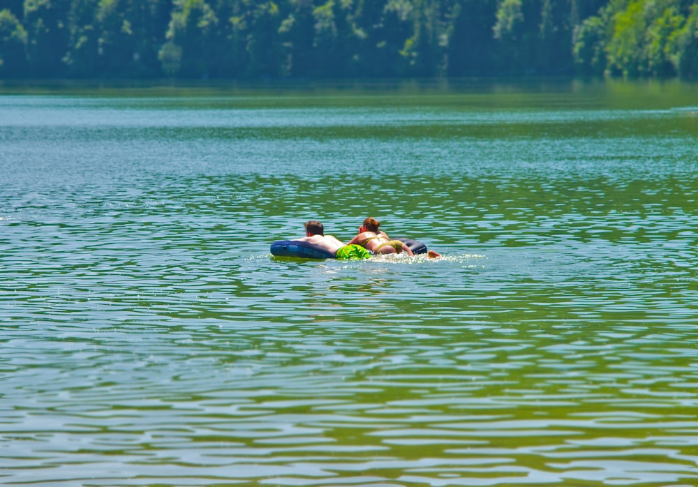 2 persone che nuotano sull'acqua verde durante il giorno