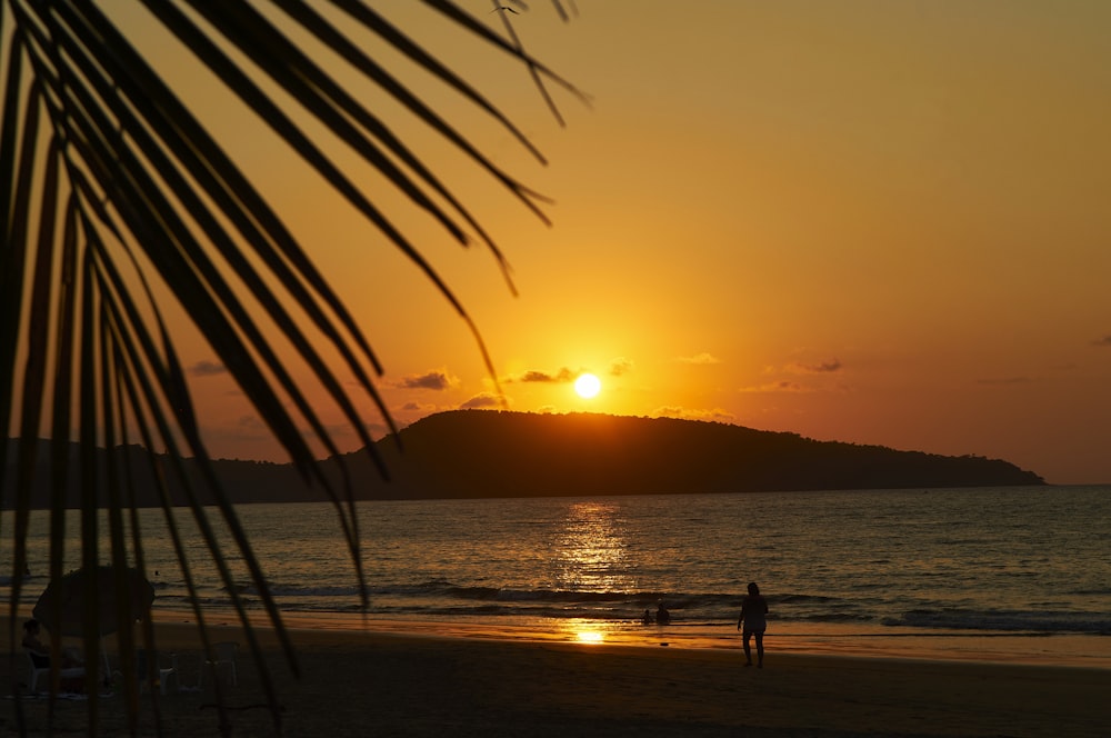 Silhouette von 2 Personen, die bei Sonnenuntergang am Strand stehen