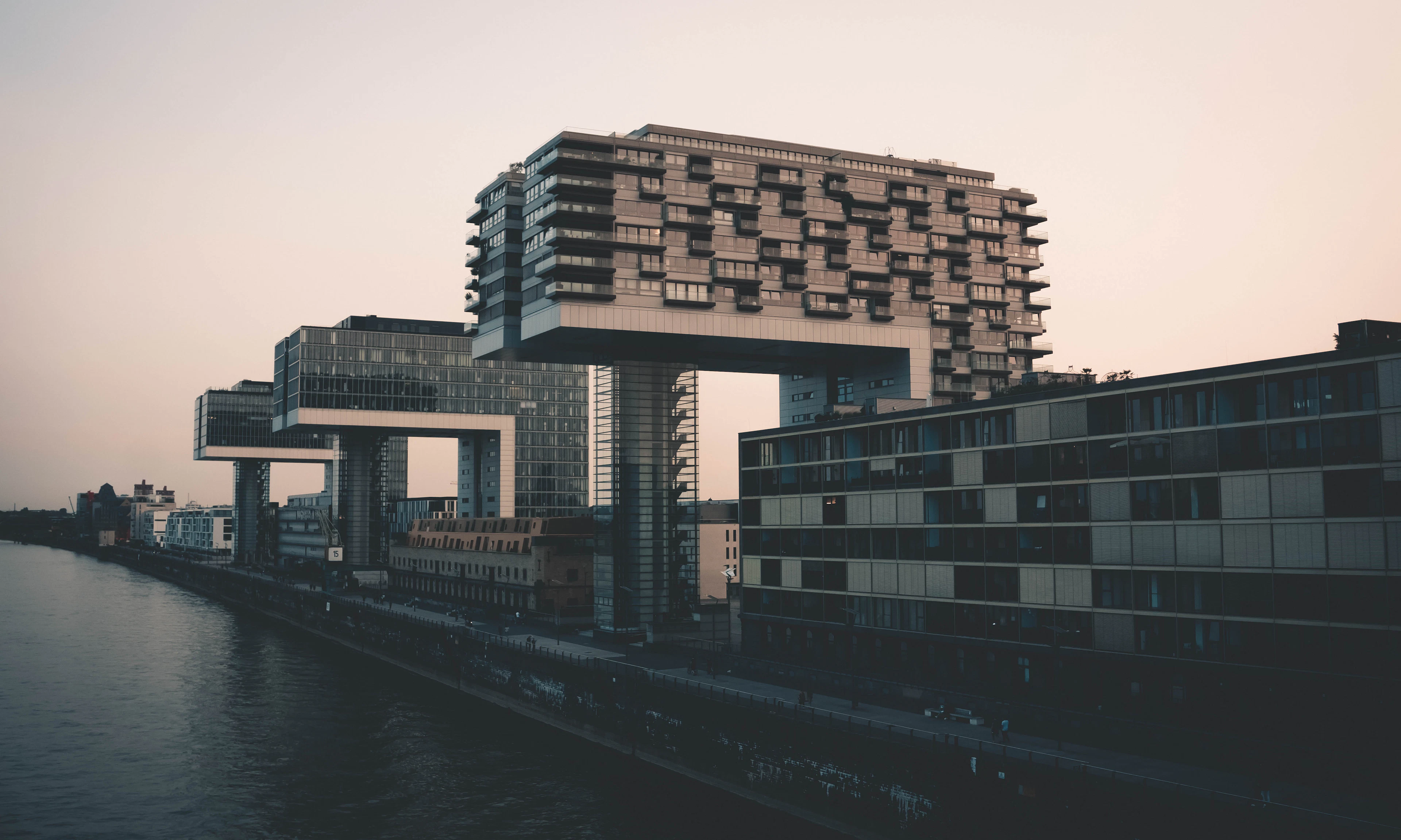 The crane-shaped Kranhaus buildings on Cologne's Rhine harbor glowing at dusk.